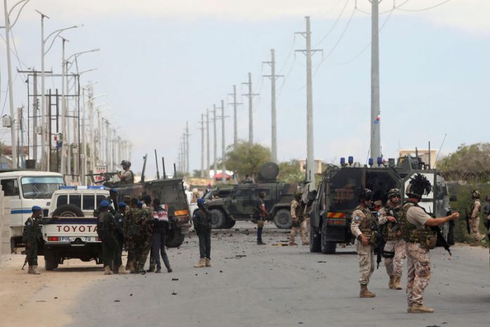 Italian and Somali security forces are seen near armoured vehicles at the scene of an attack on an Italian military convoy in Mogadishu